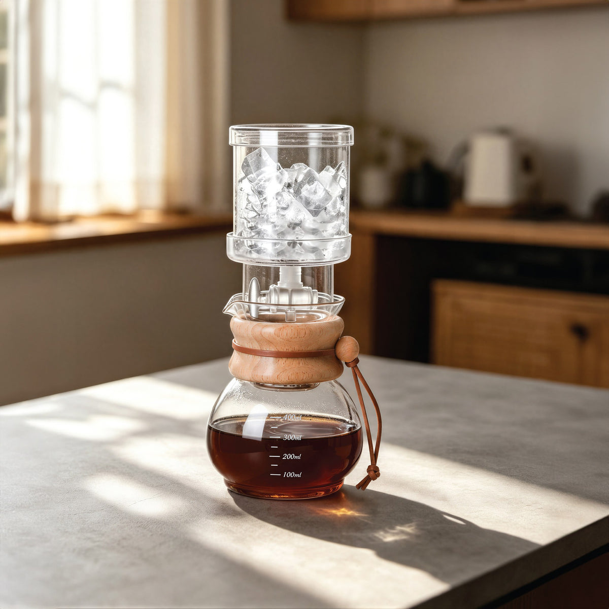 EspressoWorks cold brew drip tower filled with ice, dripping coffee into the glass carafe on a kitchen counter