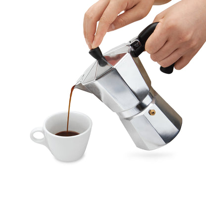 Pouring coffee from the 6-cup moka pot into a white cup