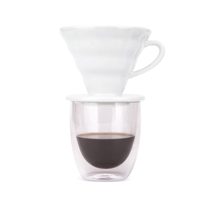 White pour over dripper on a double-wall glass of freshly brewed coffee