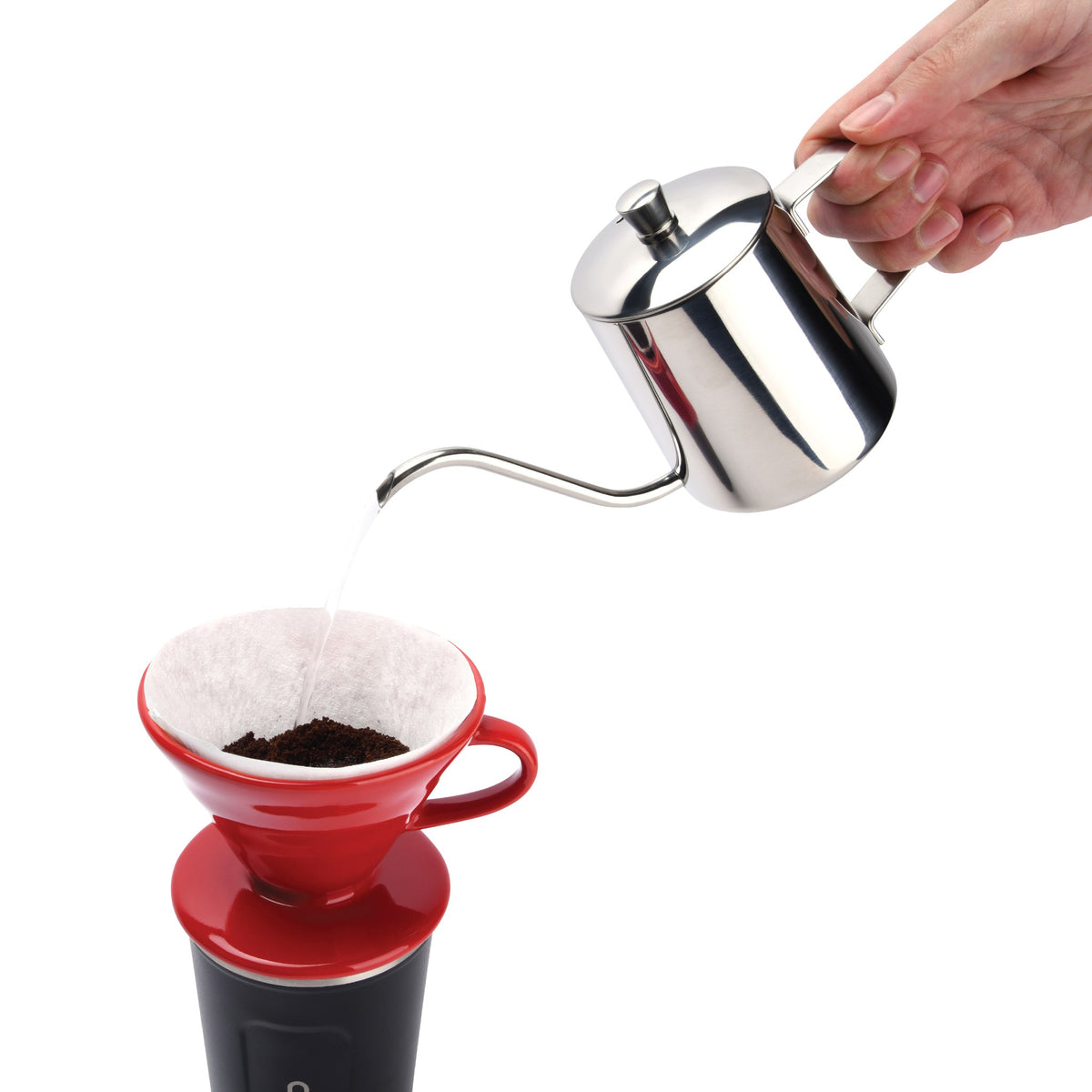 Pouring water from a gooseneck kettle over ground coffee in the red pour over dripper